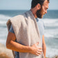 Man with a towel draped over his shoulder by the ocean