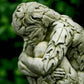 Stone sculpture of a figure with leaf-like patterns against a blurred green background