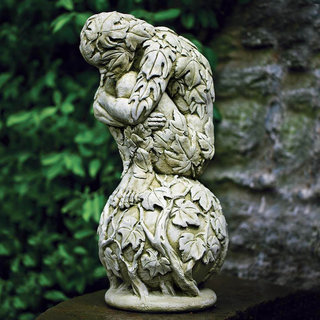 Decorative stone sculpture of a figure hugging knees with leaf patterns against a natural background