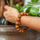 Close-up of woman's wrist wearing Bodhi Seed Bracelet as she reaches into a planter.