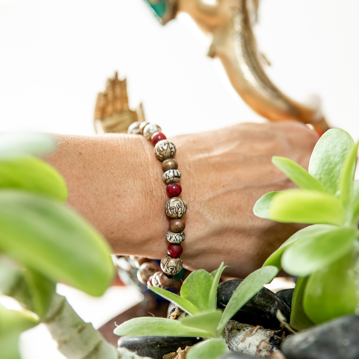 Close-up of woman's wrist reaching into planter wearing Hermit Healing Bracelet.