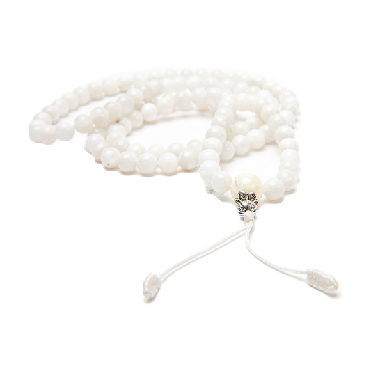 White Moonstone Mala, 108 beads rests in a pile on a solid white backdrop. The guru bead, silver accent beads, and knot are in focus and closest to the camera.