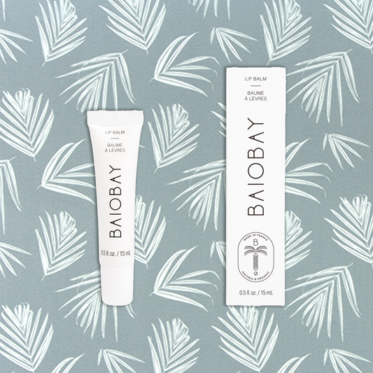 Front side views of BAIOBAY Coconut Oil Lip Balm tube and box, side by side on a botanical backdrop.